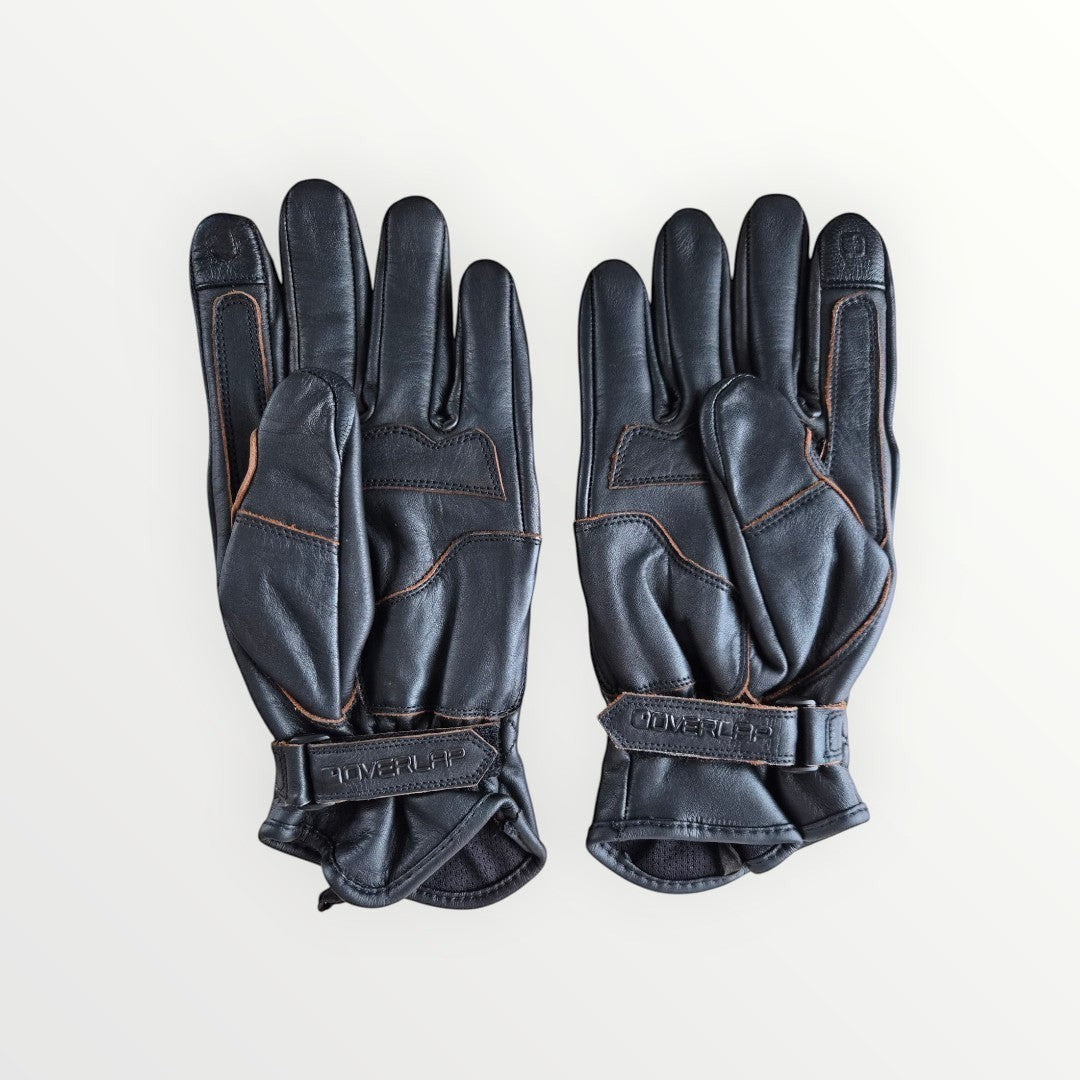 VelvetMoto black leather riding gloves with contrast stitching and adjustable wrist straps.